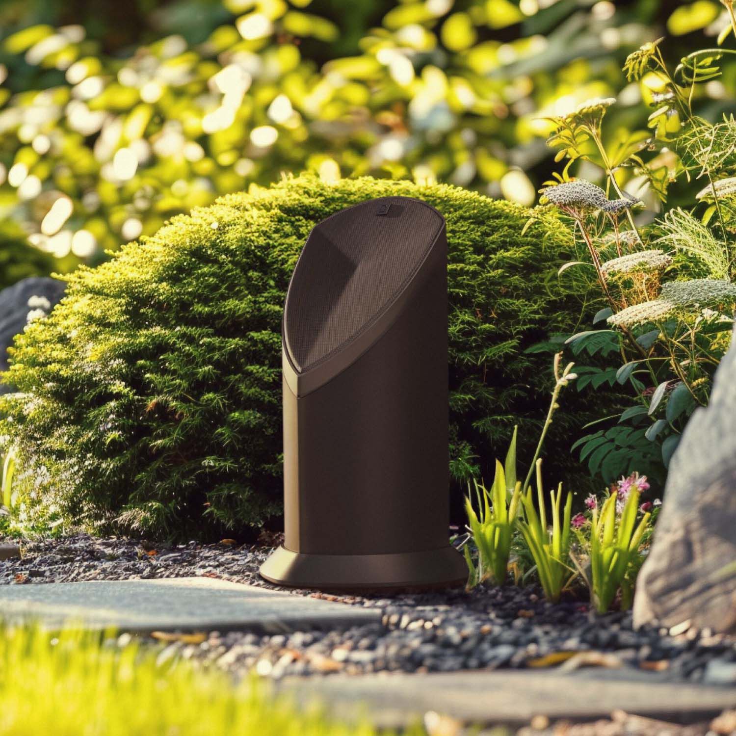 2 Definitive Technology Bollard 650 speakers sitting subtly in a garden