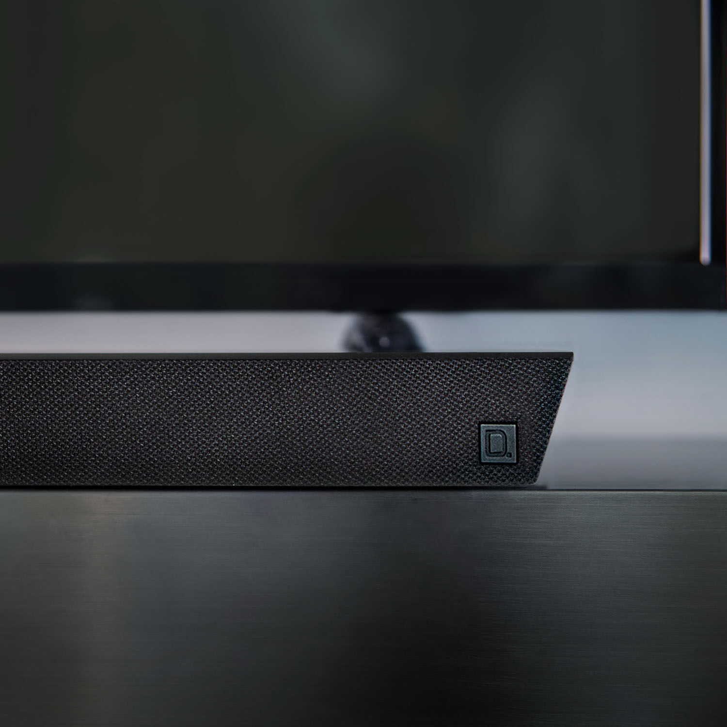 Sound bar under a TV sitting on a TV stand.