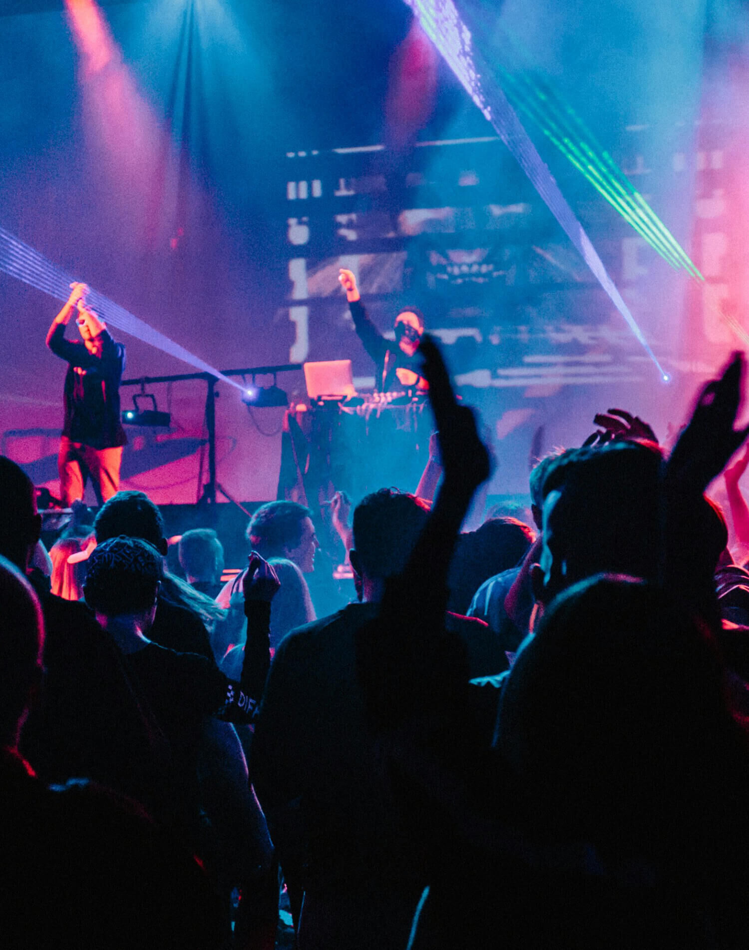 A crowd of people cheering at a live concert.